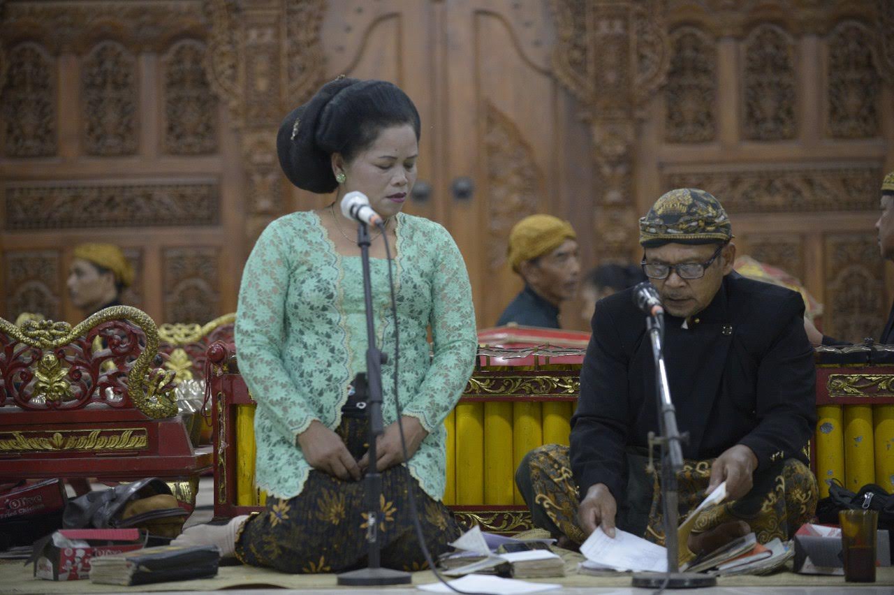 Pesinden berkebaya hijau dan pengrawit di depan gebyok kayu